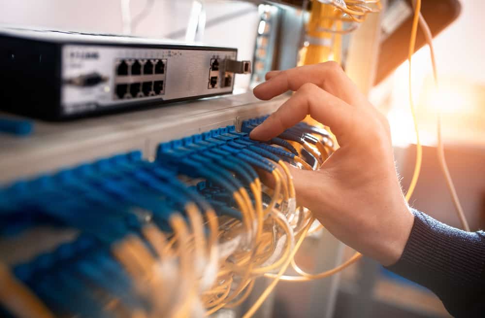 An engineer installs fiber optic patch cables at a customer site that’s part of an ISP network architecture. An engineer installs fiber optic patch cables at a customer site that’s part of an ISP network architecture.